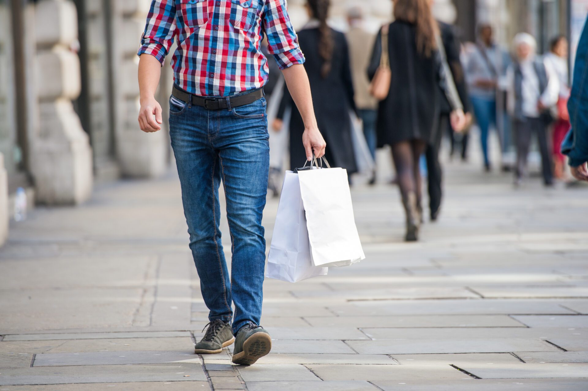 Unrecognizable man with shopping bags in the street, back view